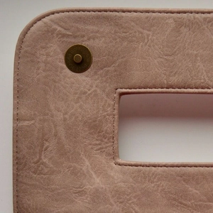 Détail de pochette en similicuir rose avec texture grainée et fermoir magnétique en bronze