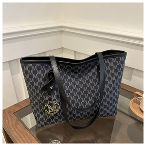 Close-up of monogrammed tote bag with gold M pendant on a wooden coffee table