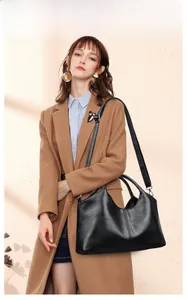 Detail of a large black textured leather tote bag with dual handles and adjustable strap