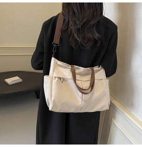 Dettaglio di una grande borsa tote in nylon beige con manici marroni indossata da una modella