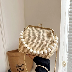 Detailed view of woven shell bag with elegant pearl handle and golden chain strap