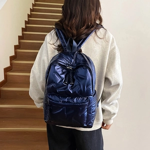 Sac à dos bouffant bleu marine métallisé porté par un mannequin dans un escalier