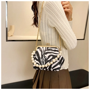 Zebra print retro clasp bag with golden chain strap and pearl handle shown on model