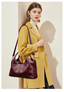 Detail of burgundy leather handbag with metallic hardware and detachable shoulder strap