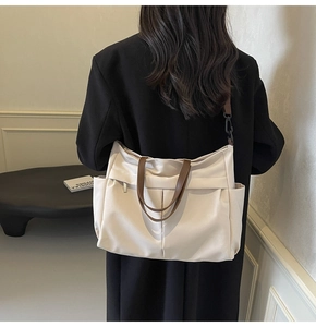 Vista posteriore modella con grande borsa tote in nylon bianco sporco e manici marroni