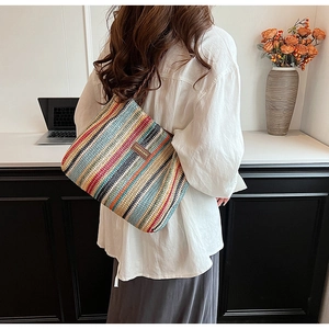 Close-up of woven tote bag with colorful stripes and leather label in a lifestyle setting