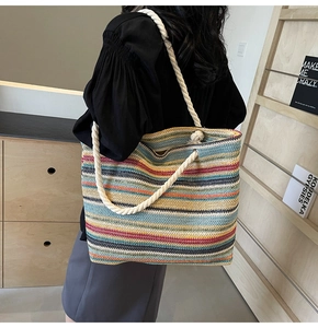 Détail d'un sac cabas tissé à rayures colorées avec poignées en corde blanche et œillets