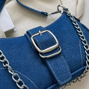 Dettaglio borsa a tracolla in denim blu con cuciture bianche e fibbia in argento