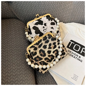 Close-up of leopard and cow print shell bags with pearl handles on a sofa