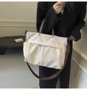 Dettaglio della borsa tote in nylon con manici in pelle marrone e tasca anteriore