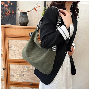 Detail of army green corduroy hobo bag featuring black and white striped shoulder strap
