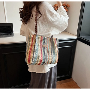 Close-up of colorful striped woven tote bag featuring a leather logo tag and braided handles