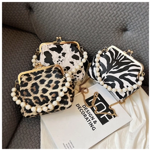 Close-up of leopard and cow print shell bags with pearl handles and gold chain straps