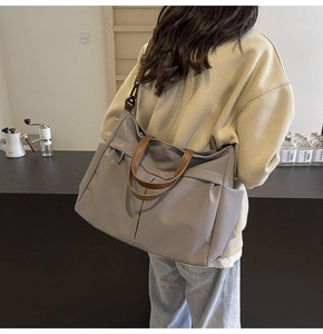 Dettaglio di una grande borsa tote in nylon con manici in pelle e tracolla regolabile