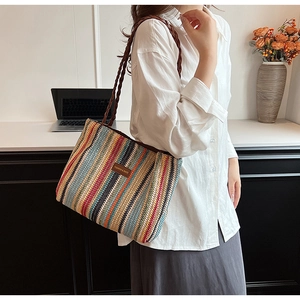 Detail of colorful striped woven tote bag with brown leather tag and long shoulder strap
