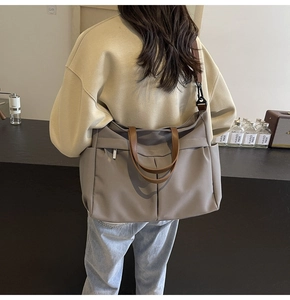 Dettaglio della borsa tote in nylon grigio con cinturini in pelle e tasca frontale