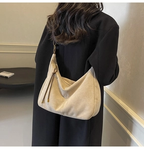 Detail of minimalist beige suede hobo bag with adjustable drawstring on female model