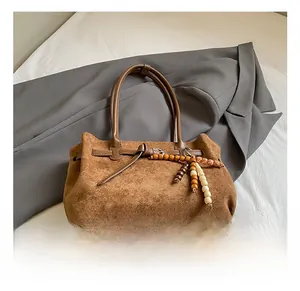 Dettaglio macro della borsa tote in pelle scamosciata marrone con pendente in legno