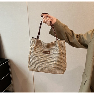 Detail of hand-woven straw tote with striped pattern and fashion leather brand label
