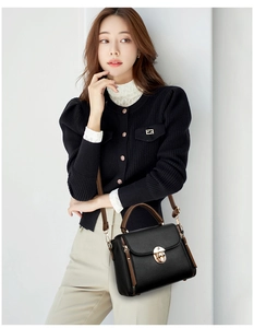 Detail view of the black lychee pattern leather handbag with gold metal clasp closure