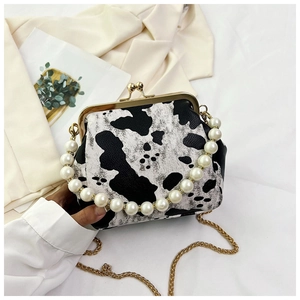 Detail of vintage shell bag with cow print leather, faux pearl handle and gold chain strap