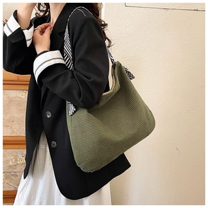 Detailed texture of green corduroy hobo bag with a stylish black and white silk scarf handle