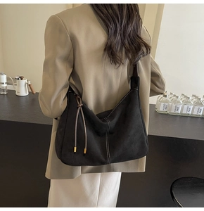 Detail of black suede hobo bag with contrast white stitching and decorative leather cords
