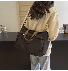 Dettaglio di una grande borsa tote in nylon con manici marroni indossata da una modella