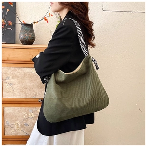 Detail of dark green corduroy tote bag with black and white striped shoulder strap