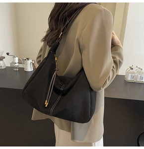 Detail of black suede Hobo bag with white contrast stitching and brown shoulder strap
