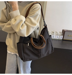 Dettaglio della borsa tote in nylon caffè con manici in pelle e tracolla regolabile