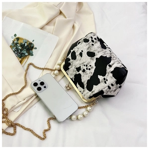 Detailed view of vintage cow print bag with golden clasp and pearl chain strap
