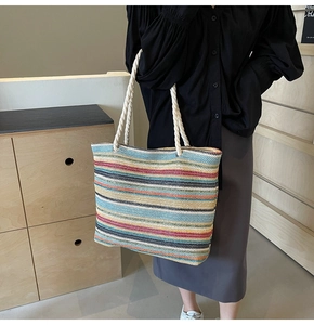 Détail du sac cabas tissé à rayures colorées avec poignée en corde crème et anneaux métalliques
