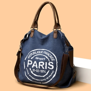 Blue canvas tote bag with brown leather handles and vintage Paris airport print