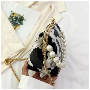 Detail of vintage shell bag featuring cow print pattern, pearl handle, and gold chain