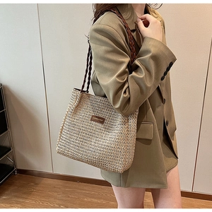 Detail of woven tote bag texture with brown leather straps and fashion brand tag