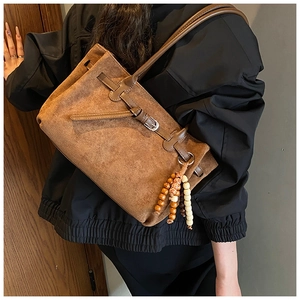 Dettaglio di una borsa tote in pelle scamosciata marrone con fibbia e perline in legno
