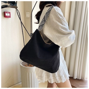Detailed close-up of black corduroy tote bag with black and white woven wide strap