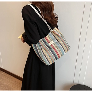 Fashionable woven tote bag with colorful stripes and leather brand label on shoulder