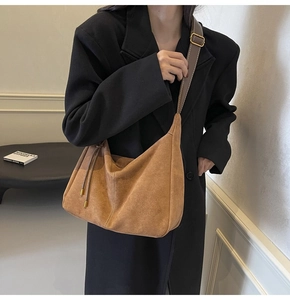 Detail of brown suede tote bag featuring adjustable leather strap and side tassels