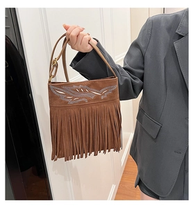 Detailed view of brown suede crossbody bag with rhinestone wings and long fringe