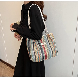 Detail of colorful striped woven tote bag with white rope handles and fashion label