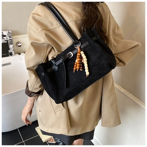 Dettaglio della borsa tote vintage in pelle scamosciata nera con ciondolo in legno