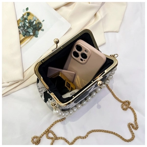 Interior capacity of marble pattern clutch showing storage for phone and cosmetics