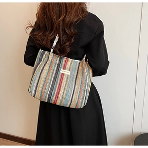 Close-up of colorful striped woven tote bag with white handles and fashion label detail