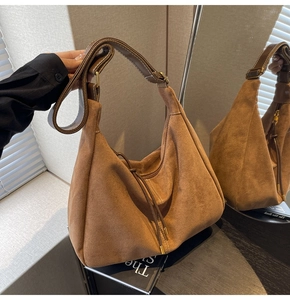 Detail of vintage brown suede hobo bag with wide leather strap and decorative stitching