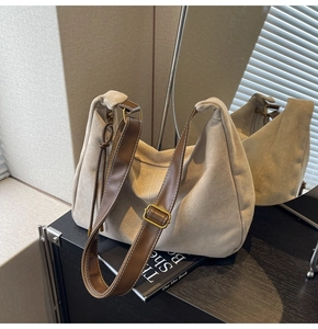 Detail of suede beige tote bag featuring brown adjustable strap and gold metal buckle