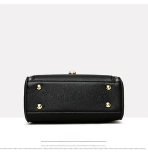 Detailed bottom view of black leather handbag with four gold metal protective feet
