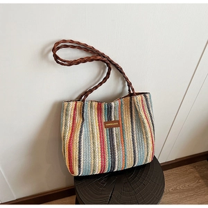 Detail of colorful striped woven tote bag with brown leather straps and fashion patch