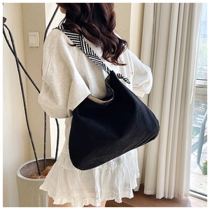 Detail of black corduroy hobo bag with stylish black and white zigzag shoulder strap
